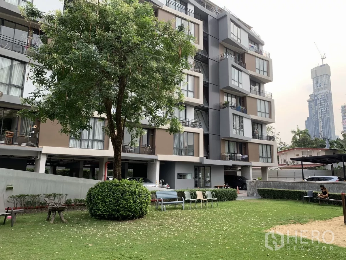 公寓 出租在Watthana, Bangkok - 绿意草坪与现代低层公寓外立面，带停车区