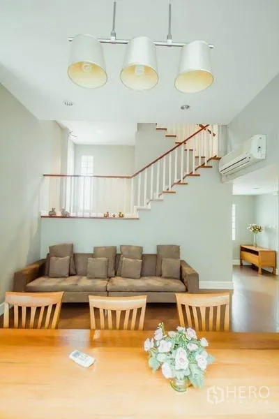 บ้าน ให้เช่าในKhlong Toei, Bangkok - โถงนั่งเล่นและรับประทานอาหารแบบโอเพ่นแพลน โซฟา โต๊ะไม้ และบันไดขึ้นชั้นบน.