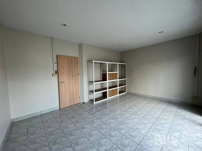 联排别墅 for rent in Phra Khanong, Bangkok - 宽敞瓷砖房间，配金属置物架和木门。