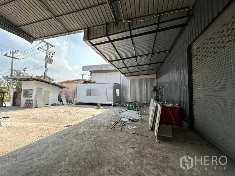 货栈 出租在Khlong Luang, Pathum Thani - 带顶装卸区，卷帘门与开阔混凝土场地。