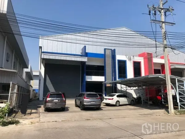 Factory for rent or sale in Bang Phli, Samut Prakan - Modern factory exterior in Bang Phli with a large roller shutter, metal facade accents and on-site parking bays.