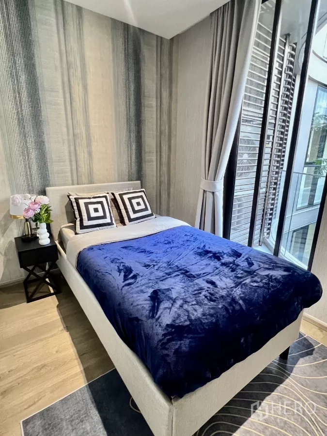 คอนโด ให้เช่าในKhlong Toei, Bangkok - ห้องนอนอบอุ่นพร้อมผ้าห่มสีน้ำเงิน และหน้าต่างสูงจรดเพดานมองเห็นคอร์ทยาร์ด
