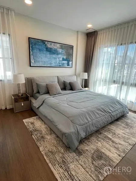 Detached House for rent in Saphan Sung, Bangkok - Bright bedroom with grey bed set, large windows with sheer drapes and abstract wall art.