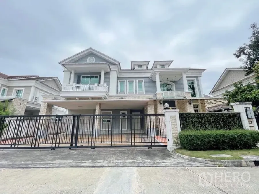 Detached House for rent or sale in Bang Phli, Samut Prakan - Grand exterior of two‑storey detached house with balconies, gated driveway, and manicured hedge.