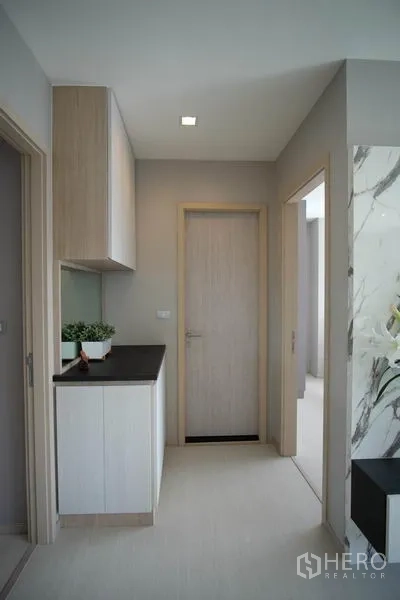 Condominium for rent in Khlong Toei, Bangkok - Hallway with light wood doors and a built-in cabinet topped with a dark counter.