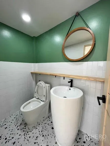 ทาวน์เฮาส์ ขายในPhra Khanong, Bangkok - ห้องน้ำชั้นล่าง ผนังสีเขียว กระจกกลม อ่างล้างมือทรงสูง และโถสุขภัณฑ์