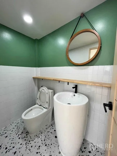 ทาวน์เฮาส์ ขายในPhra Khanong, Bangkok - ห้องน้ำชั้นล่าง ผนังสีเขียว กระจกกลม อ่างล้างมือทรงสูง และโถสุขภัณฑ์