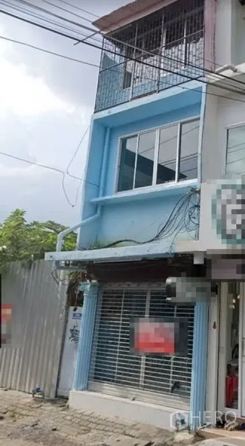 Shophouse for rent in Sathon, Bangkok - Three-storey blue shophouse exterior with glass storefront and rolling shutter in Sathon, Bangkok.