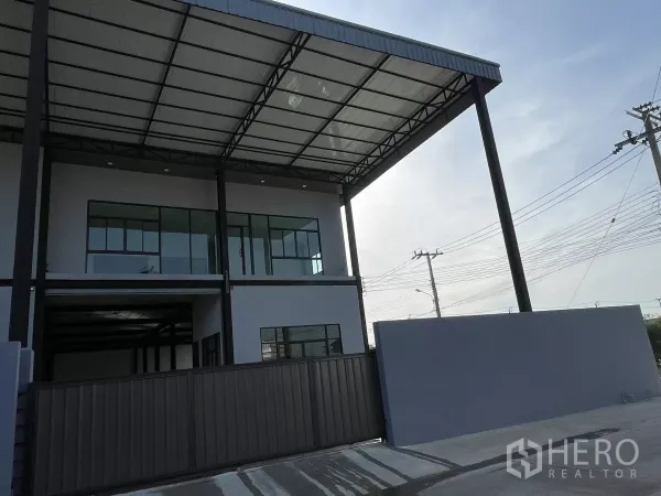 Warehouse for rent in Phra Samut Chedi, Samut Prakan - Modern two-storey warehouse exterior with high steel canopy and sliding gate.