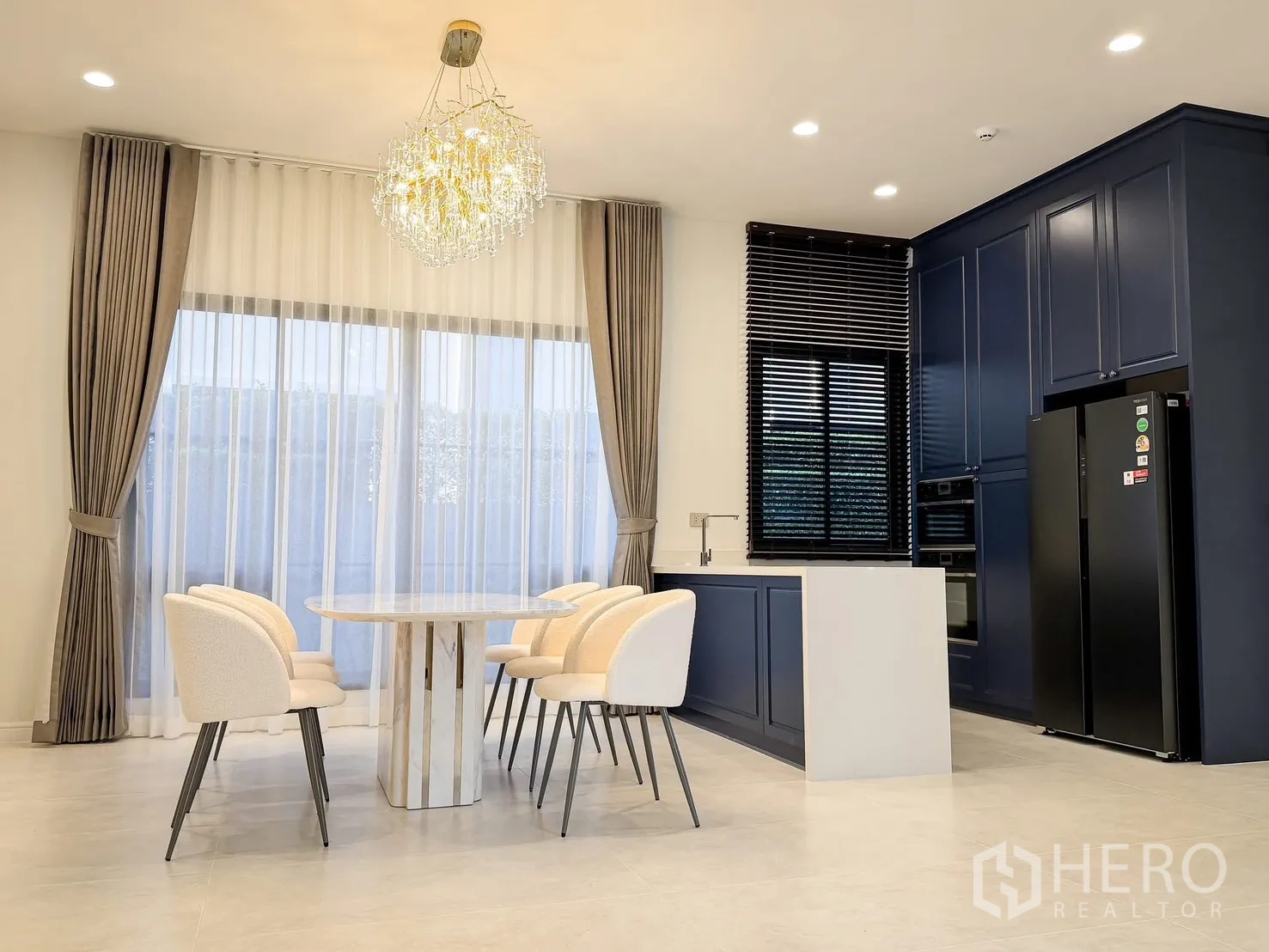 บ้านเดี่ยว for rent in Bang Khen, Bangkok - พื้นที่รับประทานอาหารและครัวบิลต์อิน โทนสีน้ำเงิน มีไอส์แลนด์ โคมแชนเดอเลียร์ และหน้าต่างบานใหญ่.