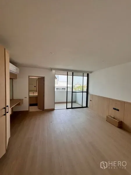 อพาร์ทเมนท์ ให้เช่าในKhlong Toei, Bangkok - มุมห้องสว่างมีประตูกระจกบานเลื่อนออกไประเบียงและพื้นไม้โทนอุ่น