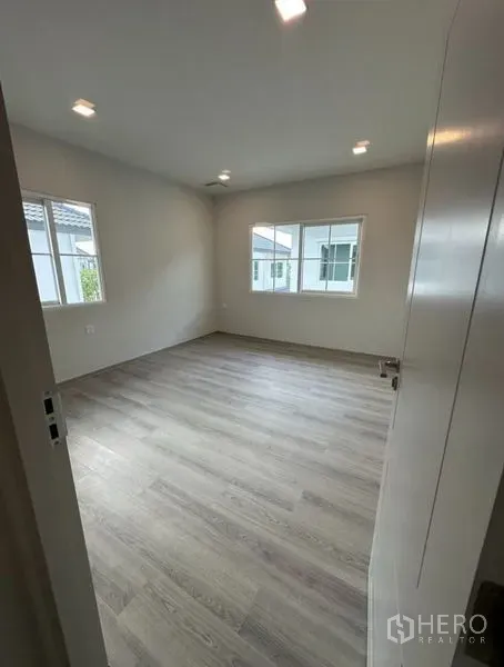 Detached House for rent - Bright empty bedroom with wood-style flooring and corner windows allowing natural light.