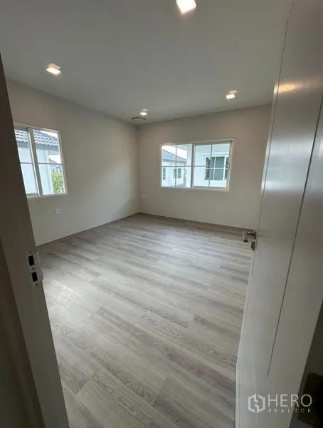 Detached House for rent - Bright empty bedroom with wood-style flooring and corner windows allowing natural light.