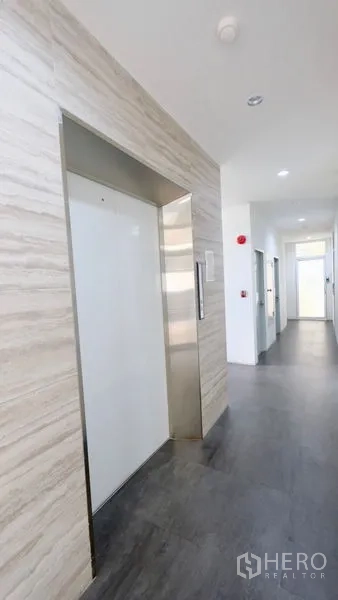 办公空间 出租在Bang Rak, Bangkok - 现代办公楼电梯大堂，石纹墙面与灰色地板，环境整洁。