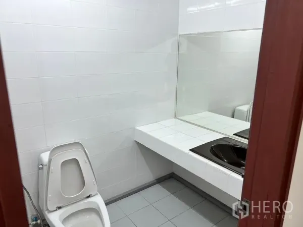 办公空间 出租在Pathum Wan, Bangkok - 干净的办公室卫生间，白色瓷砖墙，坐便器与带大镜面的长洗手台。
