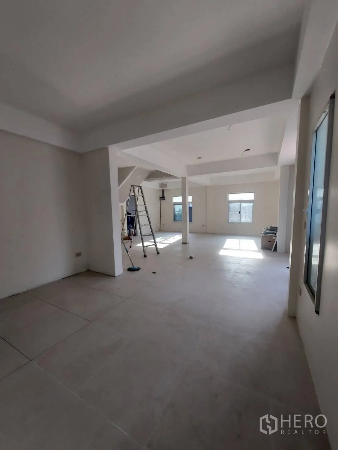 Detached House for rent in Watthana, Bangkok - Spacious open-plan room with tiled floors, columns and windows during finishing.