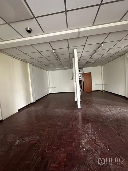 Shophouse for rent in Sathon, Bangkok - Long rectangular floor plate with support column, grid ceiling, and parquet flooring.