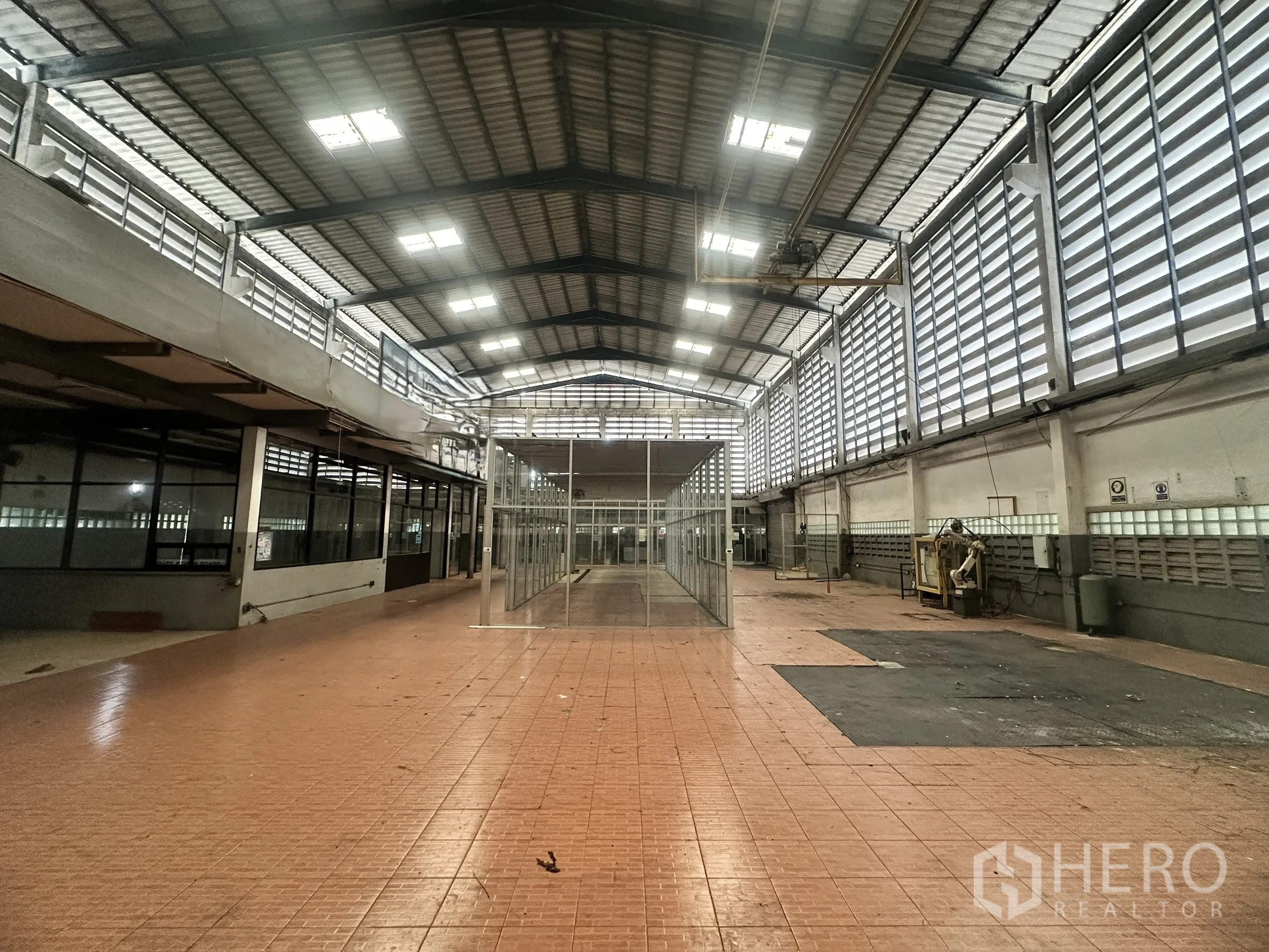 Factory for sale in Bang Bua Thong, Nonthaburi - Central production zone with tiled floor and glass cubicles under a metal roof.