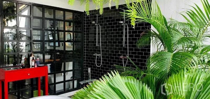 ทาวน์เฮาส์ ให้เช่าในKhlong Toei, Bangkok - ห้องน้ำเอาต์ดอร์บนระเบียง กระเบื้องสีดำ ฝักบัวคู่ ผนังกระจกบล็อก โต๊ะสีแดง และต้นไม้เขียวชอุ่ม