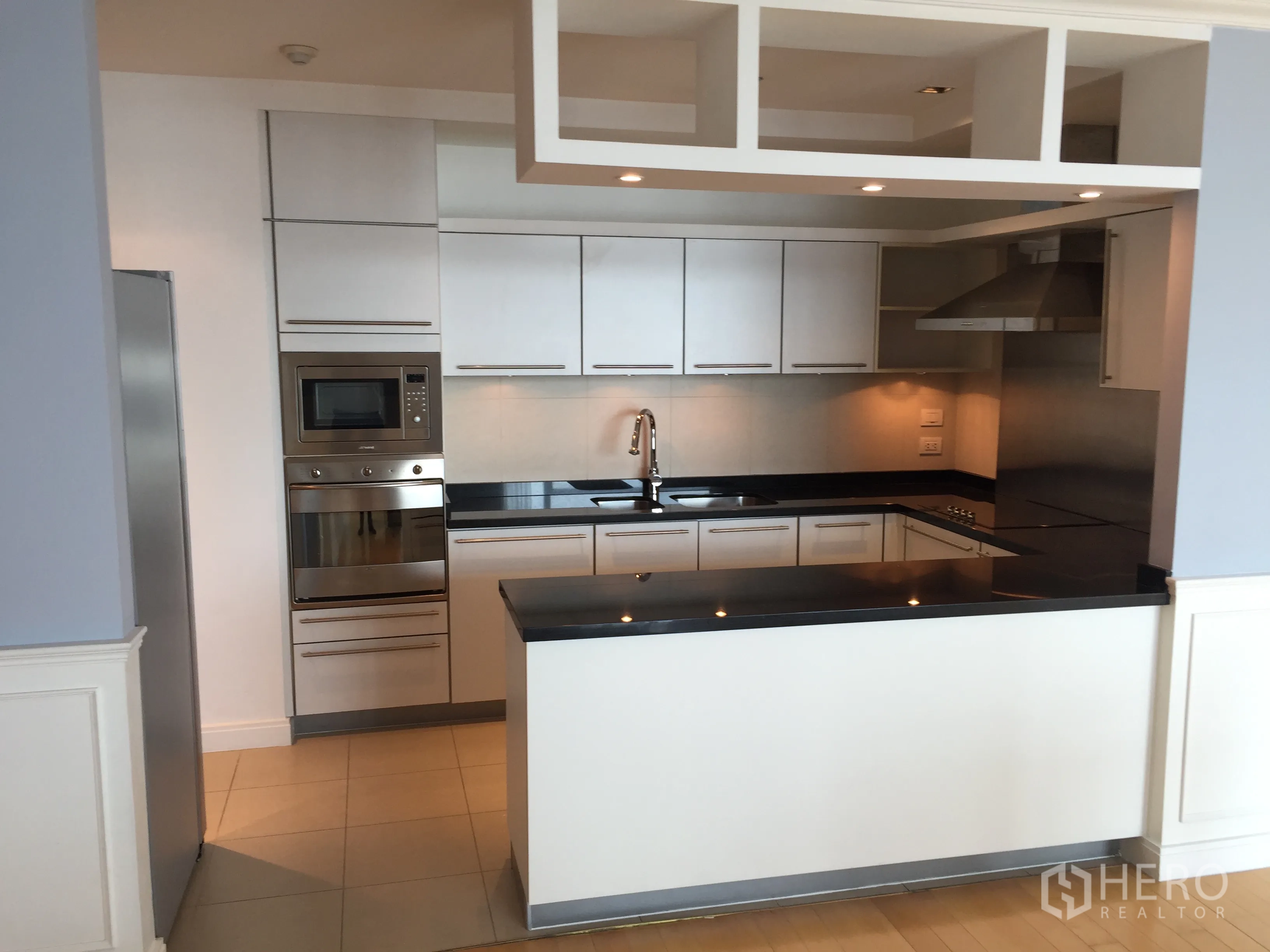 Condominium for rent in Pathum Wan, Bangkok - Modern U-shaped kitchen with white cabinetry and built-in appliances.