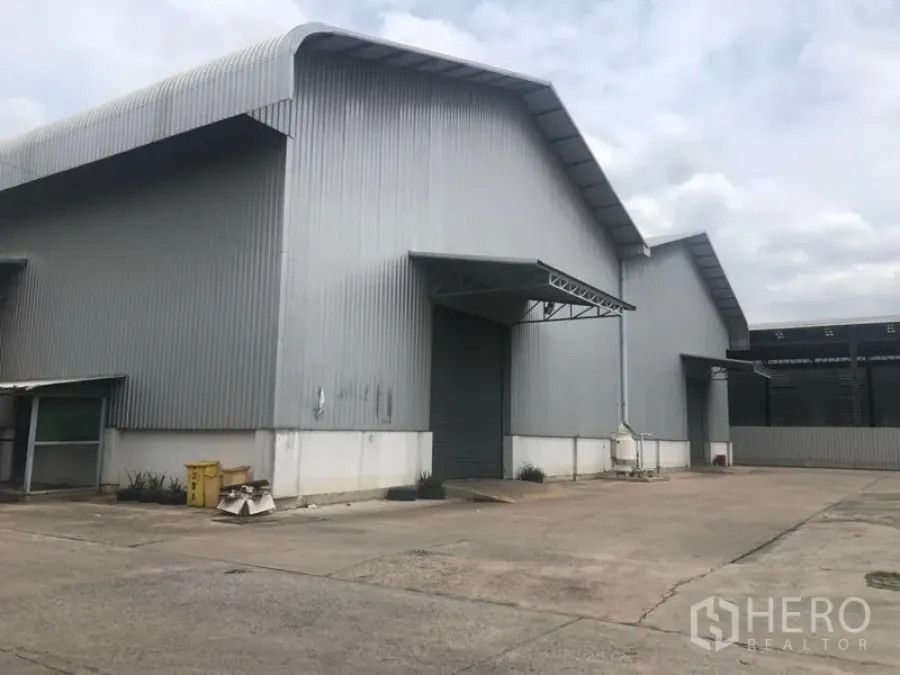 工厂 出租在Khlong Luang, Pathum Thani - 钢板外墙的工厂外观，双坡高屋顶，装卸雨棚与宽阔车道（Khlong Luang）。