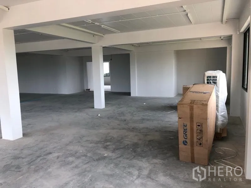 Office Space for rent in Lat Krabang, Bangkok - Corner of the office space showing structural columns, grey floor and equipment boxes.