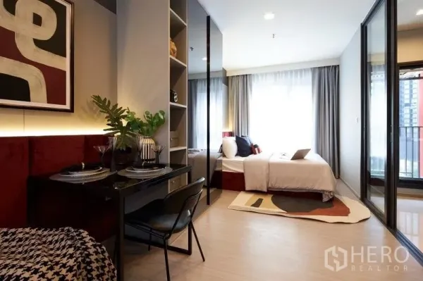 คอนโด ขายในRatchathewi, Bangkok - ห้องสตูดิโอแสดงโต๊ะทำงาน เตียง และประตูบานเลื่อนไปยังระเบียง