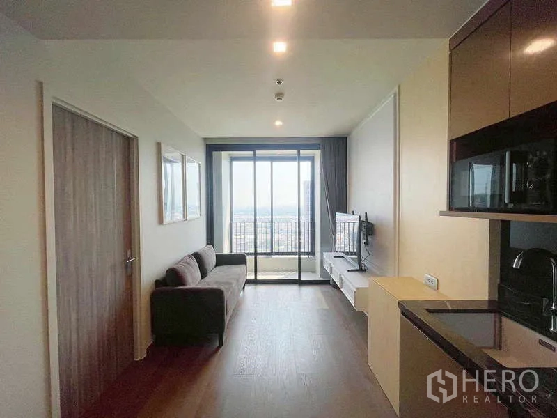 คอนโด ให้เช่าในKhlong Toei, Bangkok - ห้องนั่งเล่นสว่าง พร้อมโซฟา ครัวขนาดกะทัดรัด และประตูกระจกสไลด์ออกระเบียงวิวเมือง