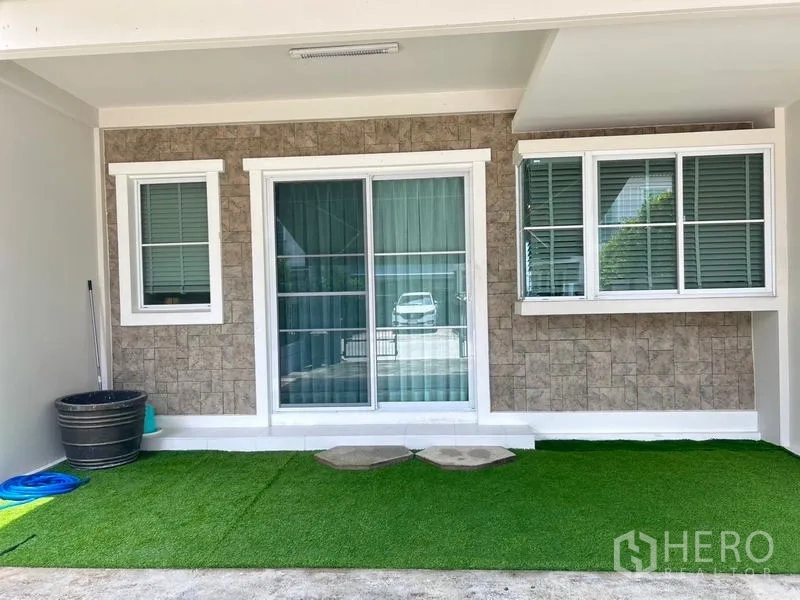 ทาวน์เฮาส์ ให้เช่า - เฉลียงหลังบ้านแบบมีหลังคา ประตูบานเลื่อนและสนามหญ้าเทียมเรียบร้อย.