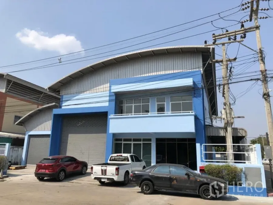 Factory for rent in Pathum Thani - Modern blue factory facade with office and front parking bays in Khlong Luang.