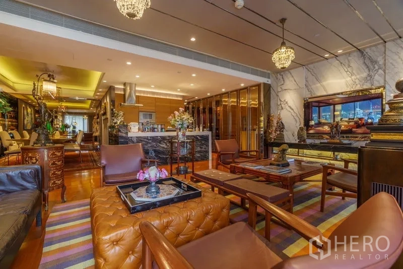 Condominium for sale in Yan Nawa, Bangkok - Living room view to kitchen with marble TV wall, pendant lighting and colorful rug.