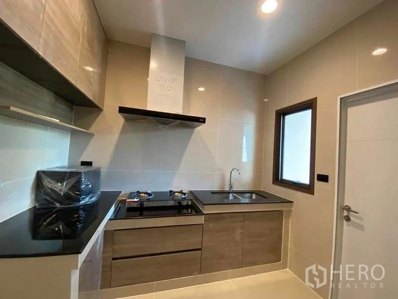 Detached House for rent in Bang Kapi, Bangkok - Separate Thai kitchen with gas hob, range hood, cabinets and window.
