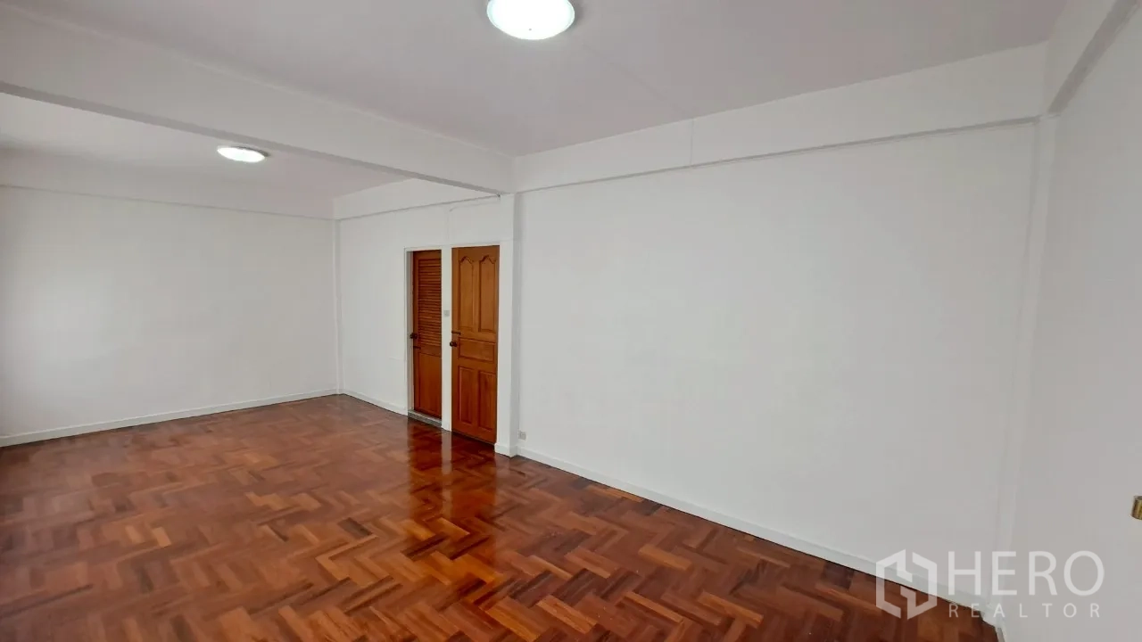 Townhouse for rent in Watthana, Bangkok - Spacious bedroom with glossy parquet flooring and wooden doors.