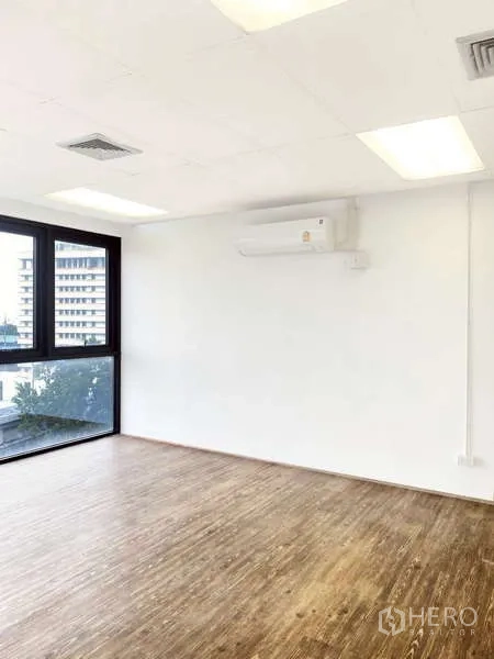 สำนักงาน ให้เช่า - มุมห้องสำนักงานสีขาว มีเครื่องปรับอากาศแบบติดผนัง หน้าต่างบานใหญ่ และพื้นไม้