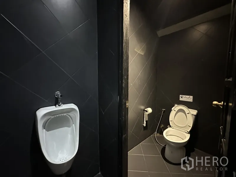Retail Space for rent in Phra Khanong, Bangkok - Dark-tiled restroom with toilet and urinal.