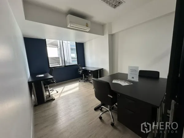 Office Space for rent in Watthana, Bangkok - Compact team room with desks, swivel chairs, large window and wall-mounted air conditioner.