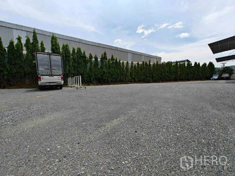 Warehouse for rent in Sam Phran, Nakhon Pathom - Expansive gravel yard suitable for truck turning, parking and container staging beside the warehouse.