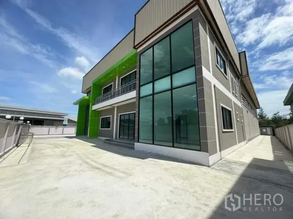 工厂 出售在Samut Sakhon - 工厂侧立面，大面积转角落地玻璃与宽阔混凝土场地。