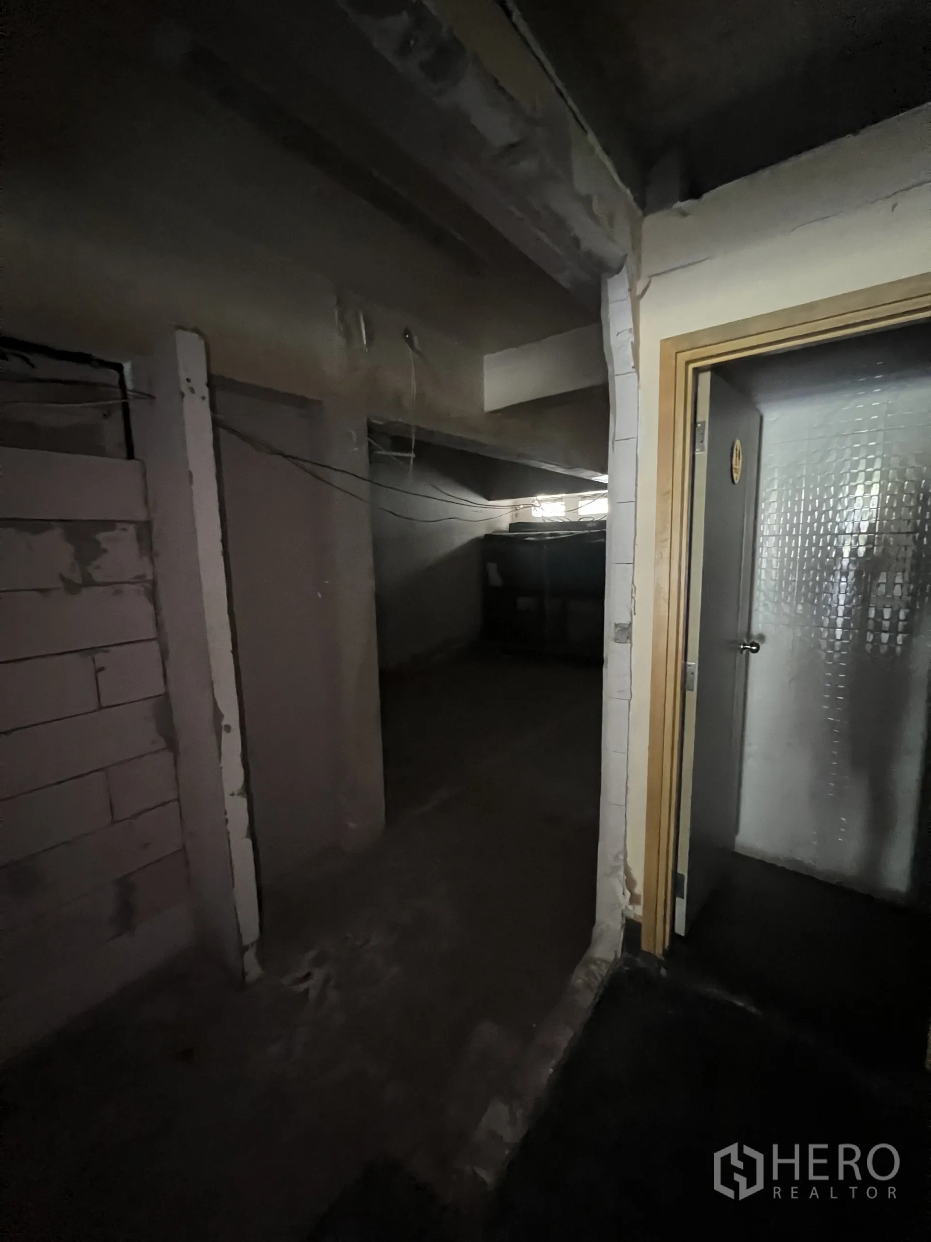 零售空间 出租在Watthana, Bangkok - 卫生间与储物区旁的走廊，外露结构与门框。