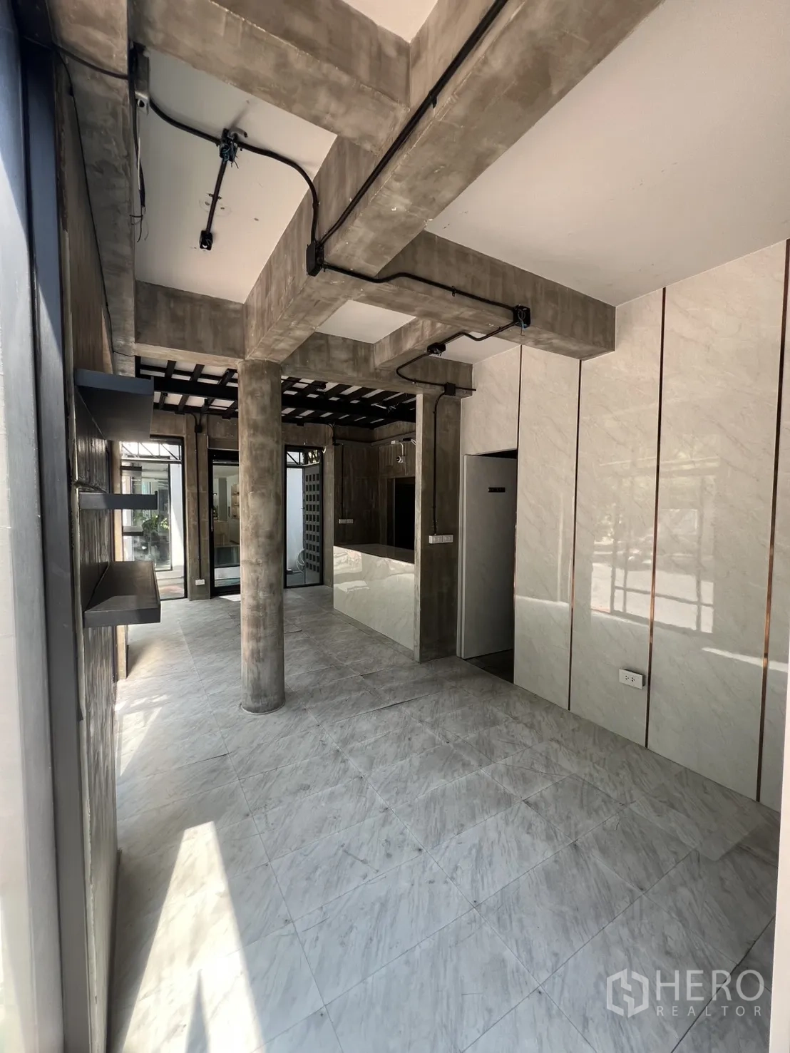 店屋 出租在Watthana, Bangkok - 一层零售区，仿石纹地砖与清水混凝土立柱。