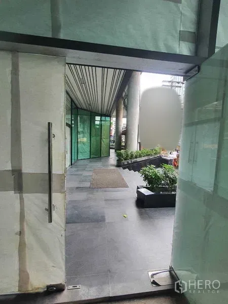 零售空间 出租在Bang Rak, Bangkok - 从店铺门口望向有顶棚的广场，瓷砖步道与绿植花槽。