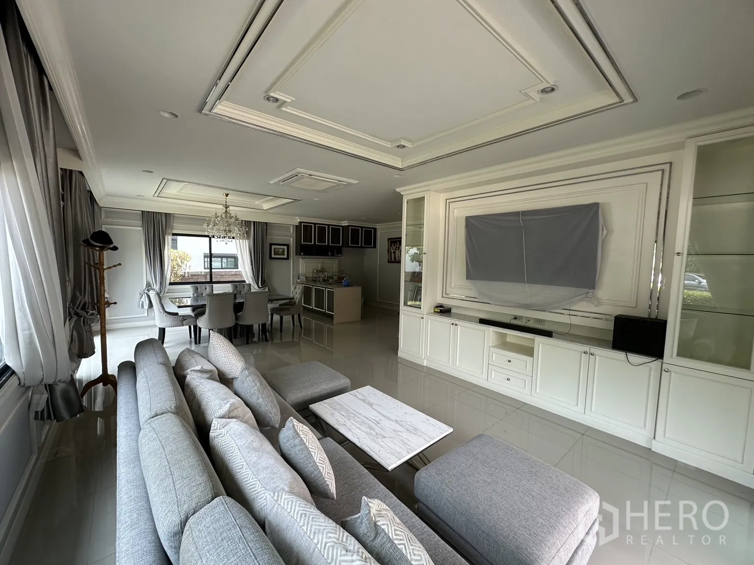 บ้าน ให้เช่าหรือขายในLam Luk Ka, Pathum Thani - โถงรับแขกและรับประทานอาหารแบบโอเพน พร้อมโซฟา โคมระย้า และชั้นทีวีบิ้วอิน