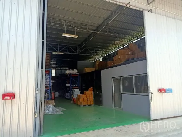 คลังสินค้า ให้เช่าในBang Kapi, Bangkok - ประตูบานสไลด์เปิดกว้าง เผยให้เห็นโกดังเพดานสูง โครงเหล็ก พื้นอีพ็อกซีสีเขียว และชั้นวางสินค้า