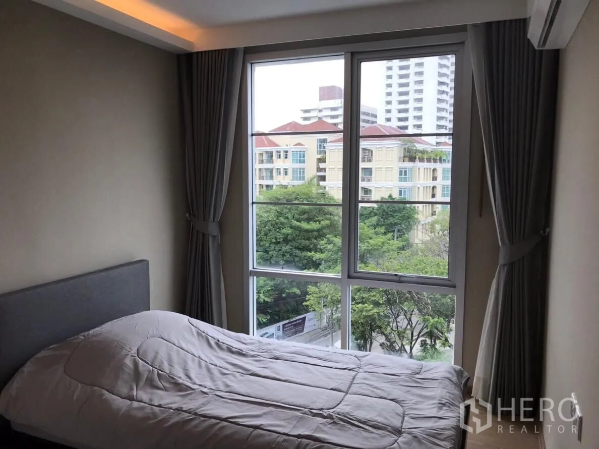 Condominium for rent in Watthana, Bangkok - Guest bedroom with wide corner windows and neighborhood view.