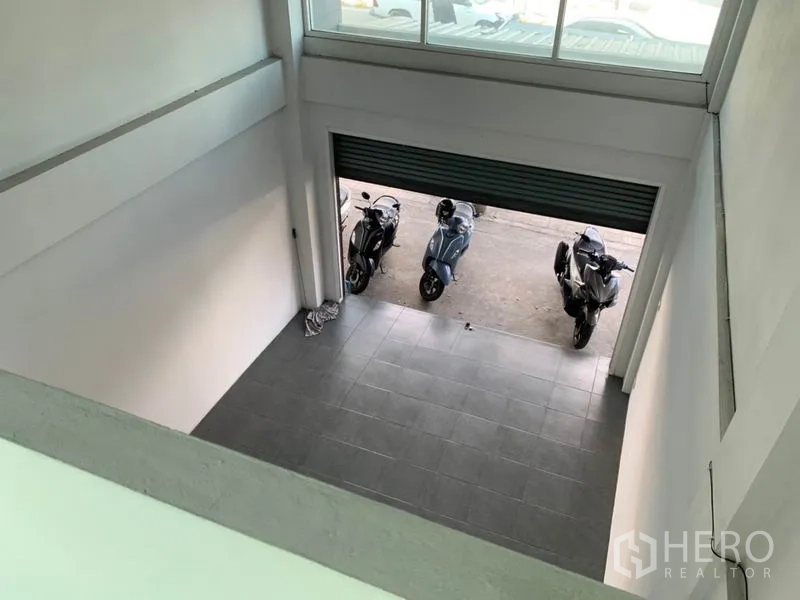 店屋 出售在Lat Phrao, Bangkok - 从夹层俯视高挑层店面大厅，灰色地砖与卷闸入口。