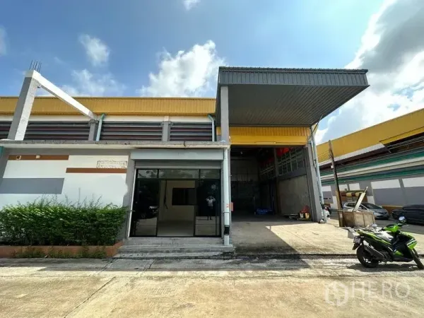 货栈 出租在Khlong Luang, Pathum Thani - 仓库外观，带有遮雨装卸棚、卷闸门和前方停车位（空銮）。