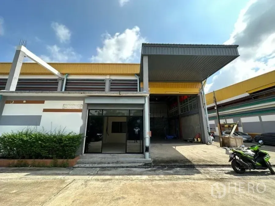货栈 出租在Khlong Luang, Pathum Thani - 仓库外观，带有遮雨装卸棚、卷闸门和前方停车位（空銮）。