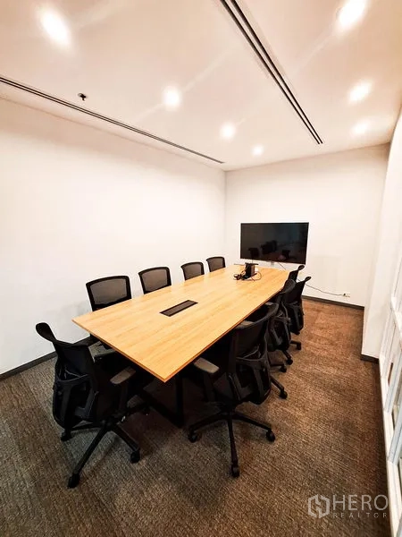 办公空间 出租在Bang Na, Bangkok - 现代会议室，长木桌、黑色椅子、吊顶射灯与墙挂电视。