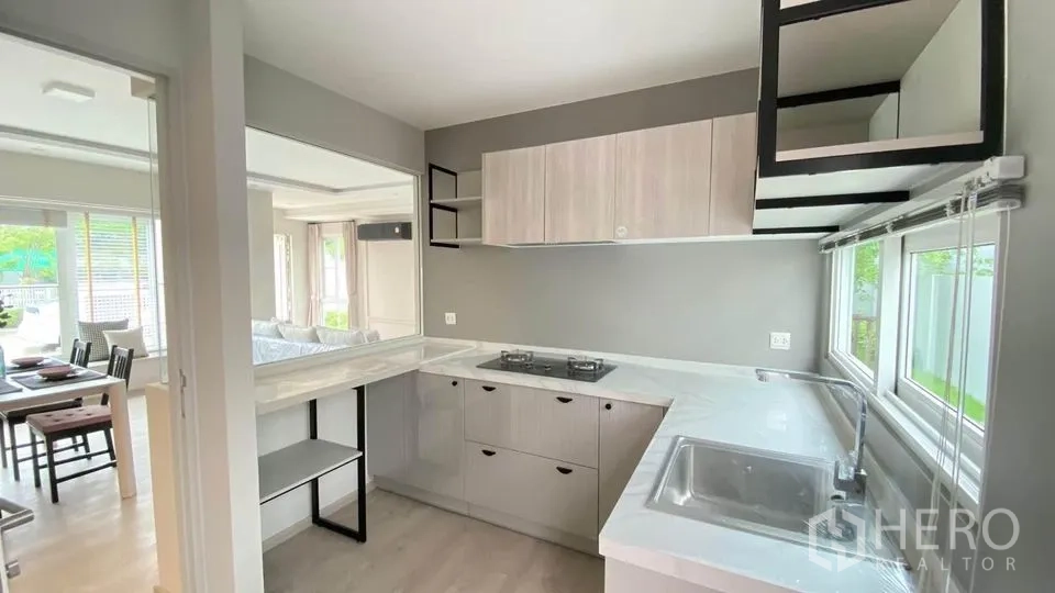 联排别墅 出租在Prawet, Bangkok - 现代L形厨房，燃气灶、水槽、窗户与吧台。