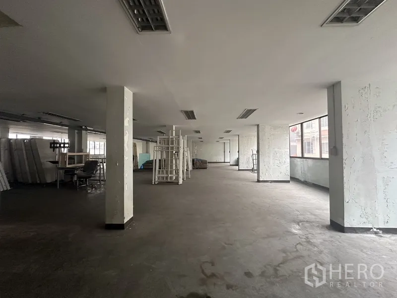 Office Space for rent in Khlong Toei, Bangkok - Raw industrial-style floor with pillars, windows and storage racks.